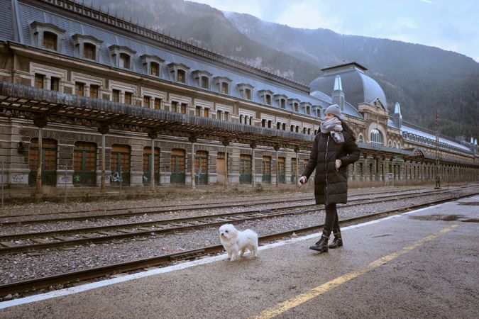 Woman with dog walking along platform at railway station