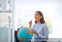 Smiling woman with hand on globe 56qml0