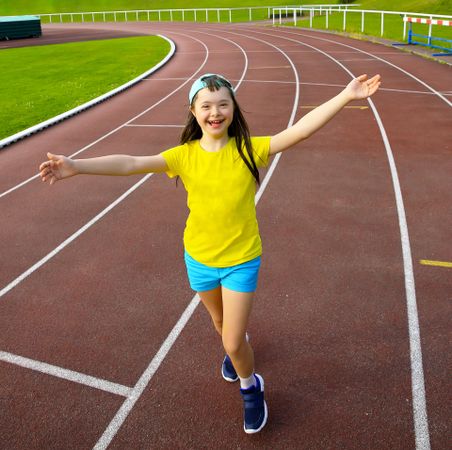 Happy girl running on track and smiling at the camera