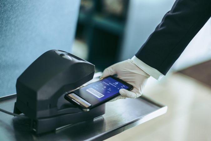 Hand of airport staff with hand glove scanning boarding pass during pandemic