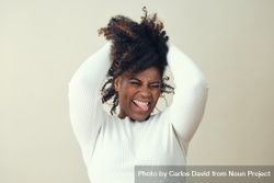 Portrait of joyful Black woman running her hands through her hair 5rMDZ0