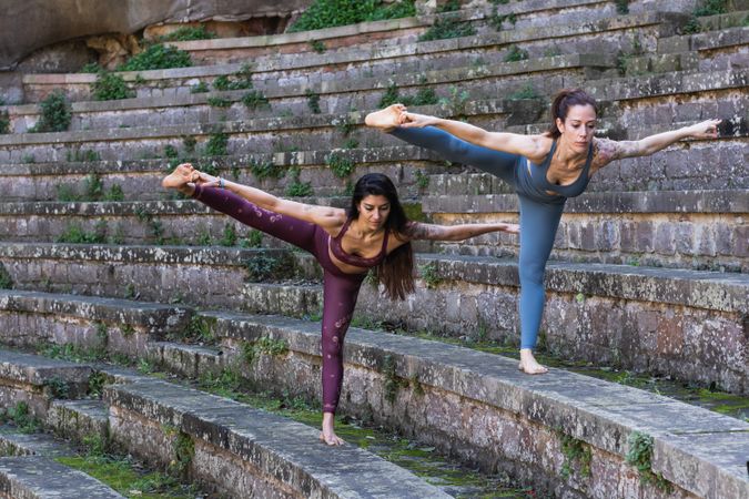 Focused women standing in Hand to Toe pose and doing yoga