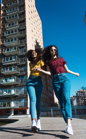 Two woman skipping in city