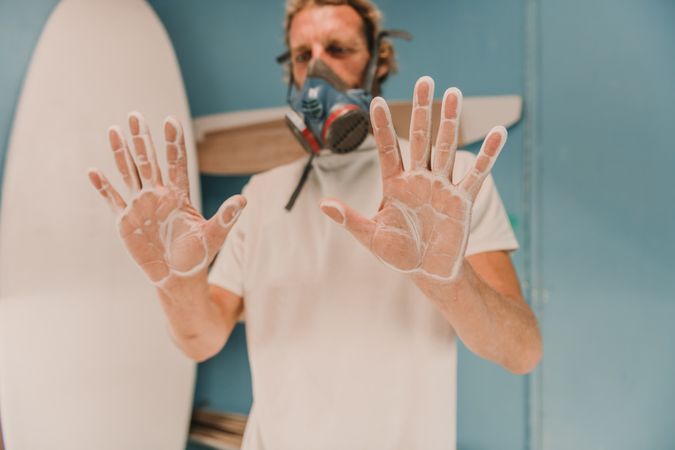 Man in respirator showing hands in dust
