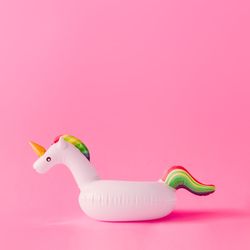 Inflatable unicorn pool toy on pastel pink background