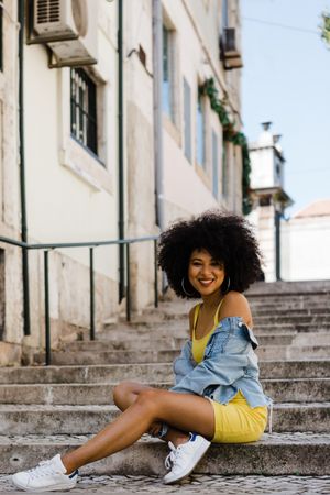 Stylish female sitting in stairs with railing outdoors
