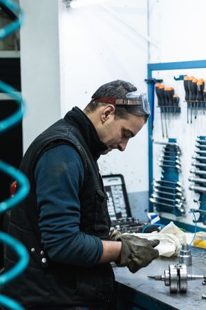 Professional mechanic using spanner while assembling vehicle engine details at workbench