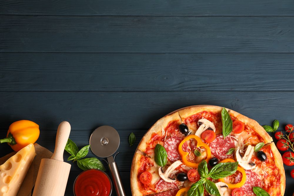 Delicious pizza and ingredients on wooden background, copy space
