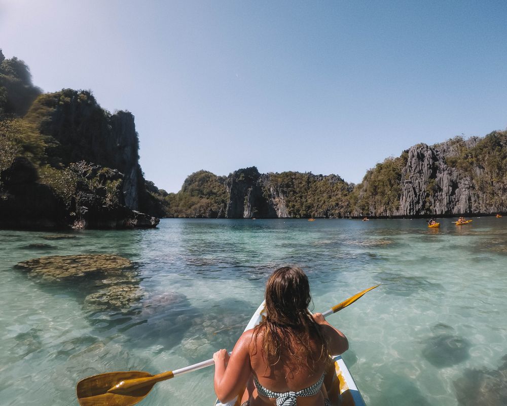 Woman in bikini riding on yellow kayak on lake