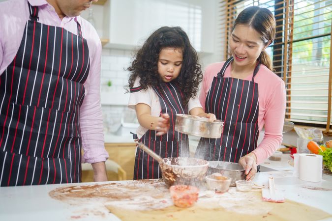 Child with parents baking together in the kitchen