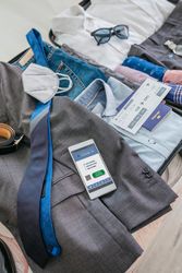 Businessman suitcase preparations for business trip with covid passport