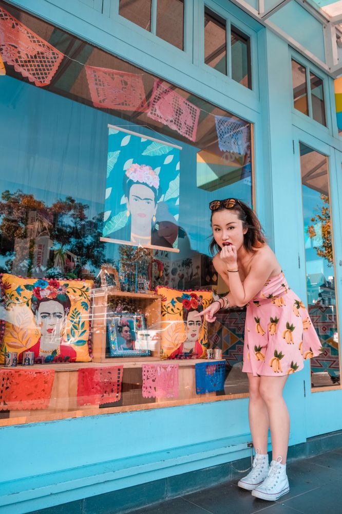 Woman in pink floral dress standing beside store front