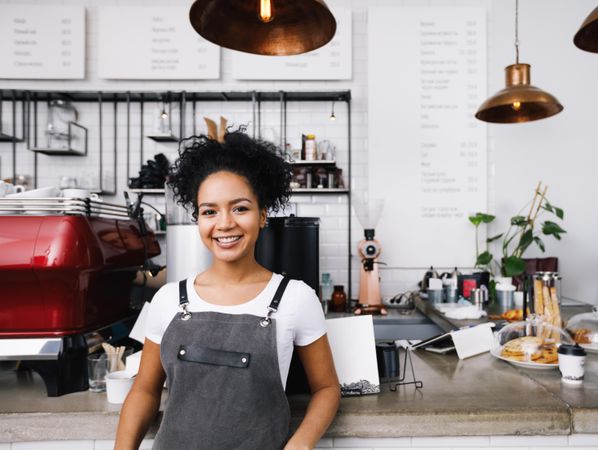 Smiling barista leaning in front of machines