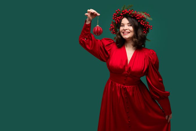Happy woman in red dress holding Christmas ornament