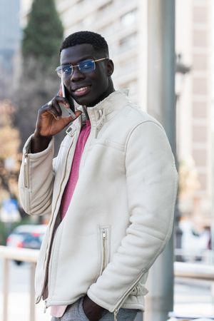 Cheerful Black businessman in eyewear talking on smartphone