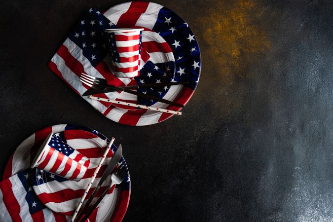 Looking down at American themed flag plates and cups on dark table with copy space