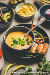 Yellow lentil soup bowl, bread, vegetable garnishes, selective focus, vertical composition 4OEMJ0