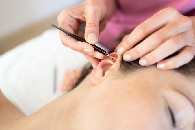 Professional doing ear treatment in clinic