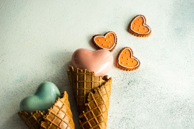 Two ceramic hearts in waffle cones on grey background sugar cookies