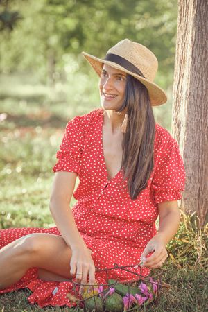 Young woman in summer dress sitting on grass