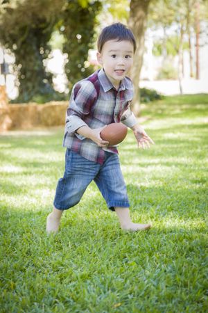 Cute Young Biracial Boy Playing Football Outside
