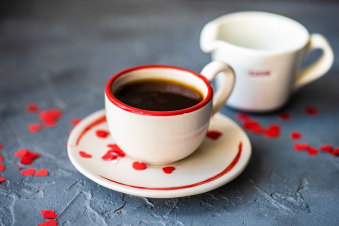 St. Valentine day card concept of coffee with red heart confetti served and cream