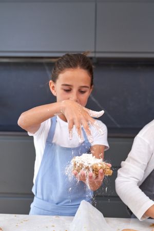 Girl sprinkling flour on dough