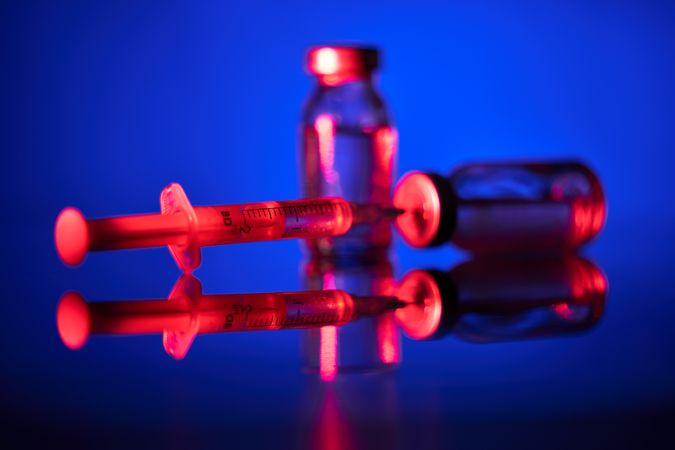 Syringe and vaccine ampoule in blue room