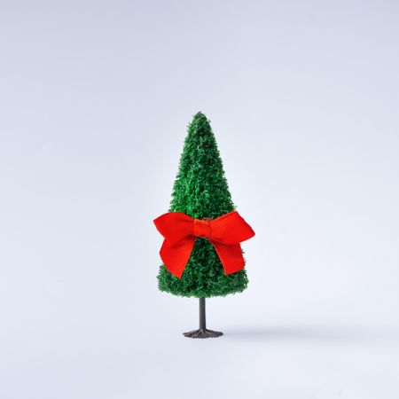 Christmas tree with red satin gift bow on light  background