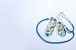 Lung shape cut out of paper with pills underneath with doctor’s stethoscope and copy space