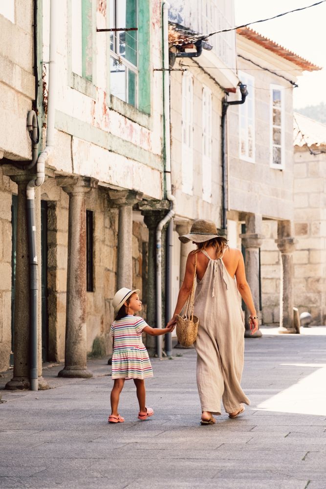 Mother and daughter walking in street along ancient building