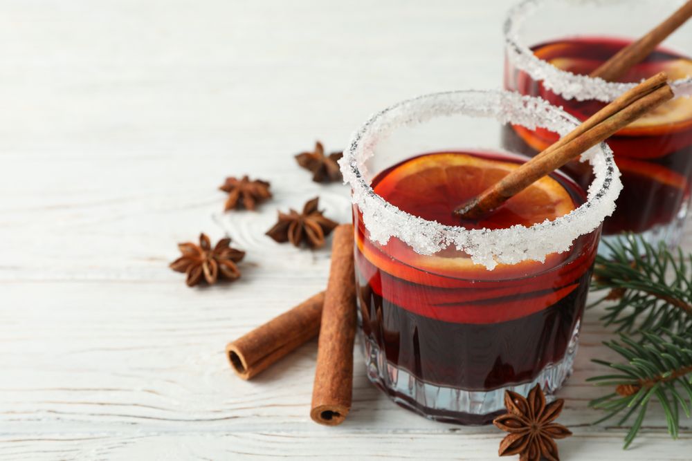 Glasses of tasty mulled wine on wooden background, space for text