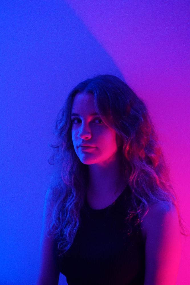 Portrait of teenage girl in purple in dark top lit studio