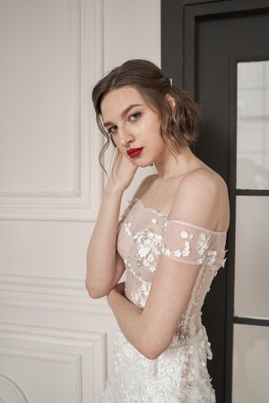 Magnificent pensive young bride in white lace dress looking at camera and pondering