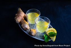 Silver tray with two yellow detox drinks with ginger and lemon 4OgW74