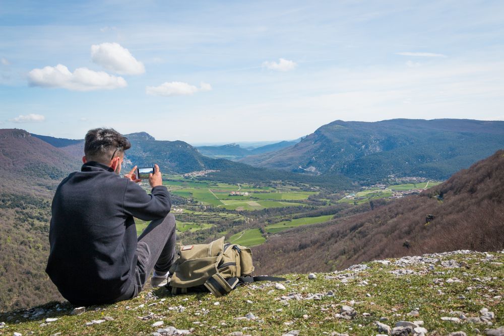Man taking picture of valley with smartphone