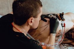 Man getting tattoo on ribs