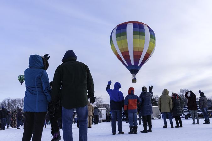 Hudson, WI, USA - February 8th, 2020: People waving at a colorful hot air balloons taking off