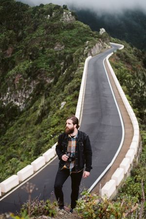 Bearded photographer looking away on mountain road