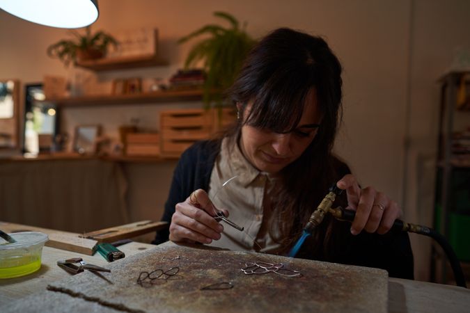 Female artisan with gas burner making handmade accessory