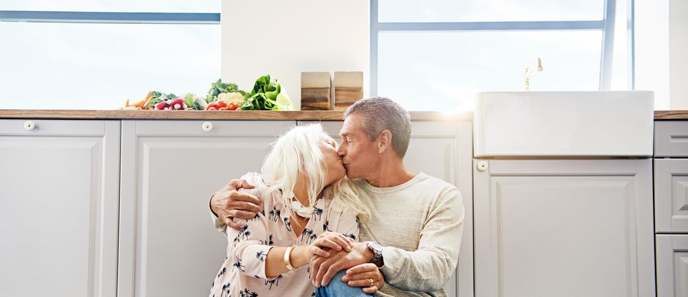 Older couple kissing on kitchen floor