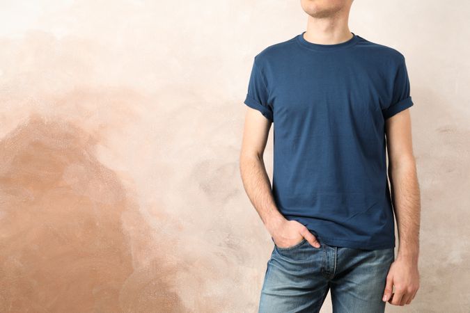 Men in blank blue t-shirt against brown background, space for text