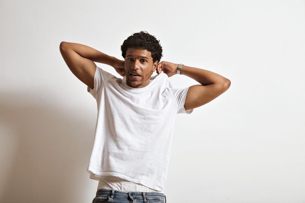 Man making funny face as he begins to take off his t-shirt