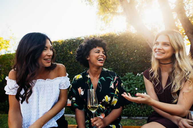 Happy young female friends hanging out and talking at outdoors party
