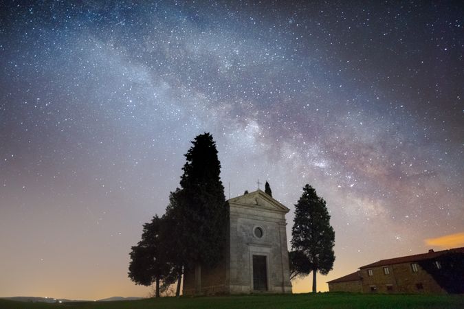 Single chapel among trees on field under stars