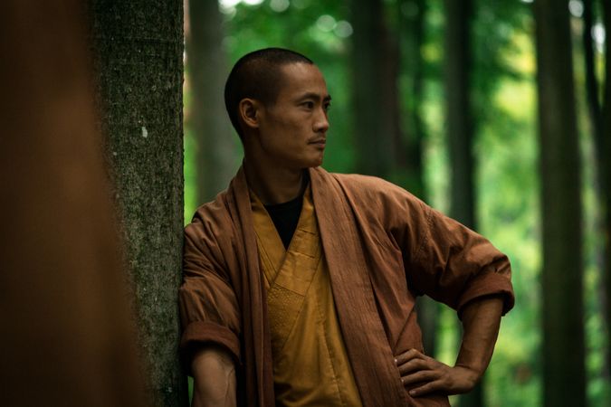 Asian guy in brown uniform resting in green forest