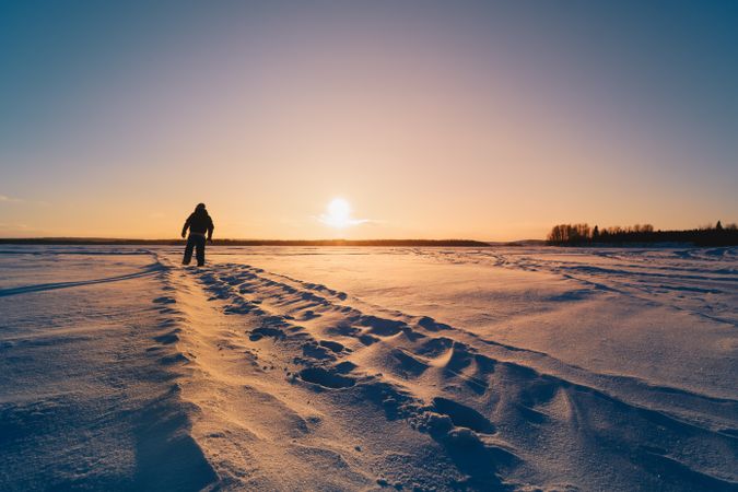 Person walking on snow during sunset
