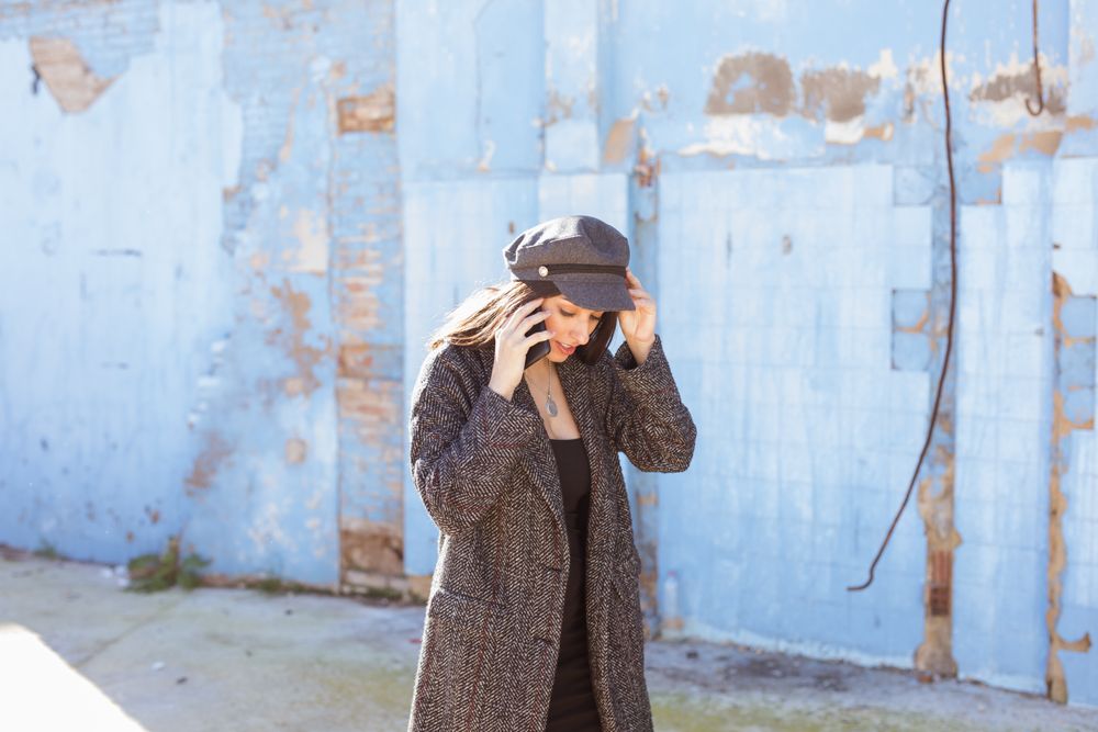 Hispanic woman talking on smartphone and going near wall and cat