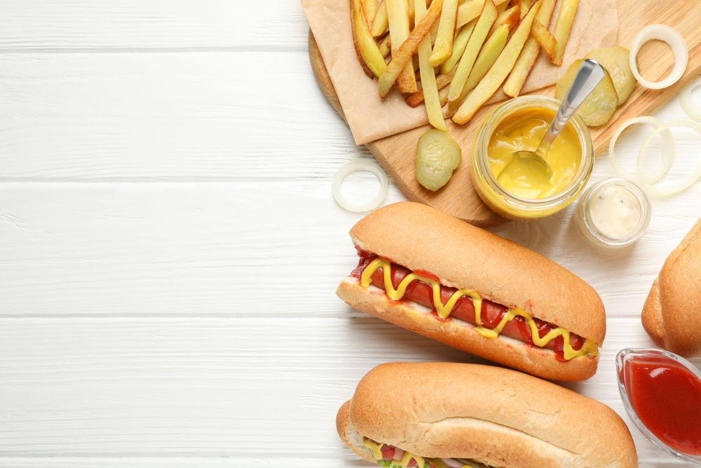 Hot dogs, fries potato and sauces on plain wooden background