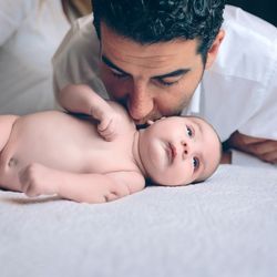Man kissing to peaceful newborn lying over bed